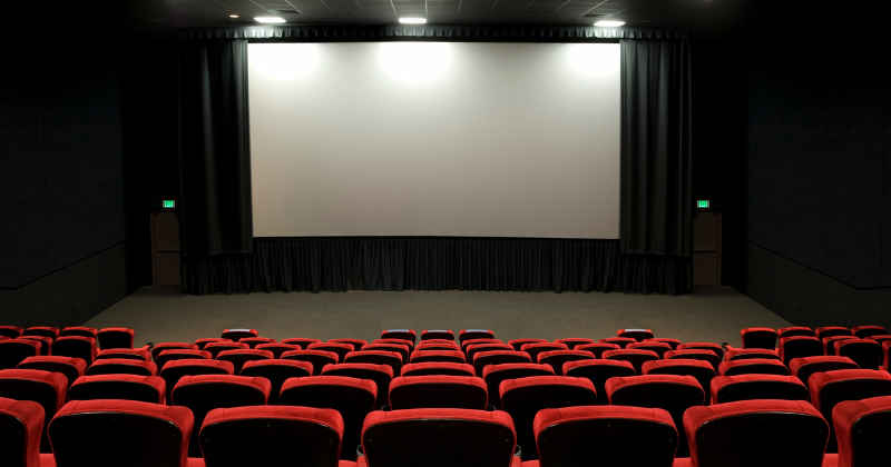 Un théâtre vide avec des sièges rouges et un écran de projection